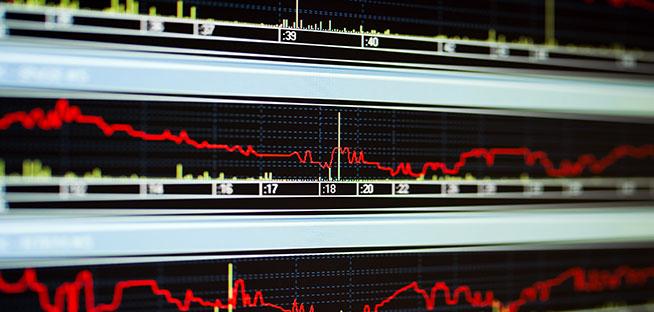 Close-up of multiple red line charts on a black screen showing market decline.