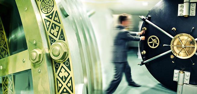 A figure in a suit walks toward a giant, open bank vault door.