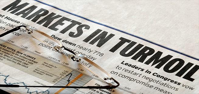 Newspaper headline reading "MARKETS IN TURMOIL" with glasses resting on the page.