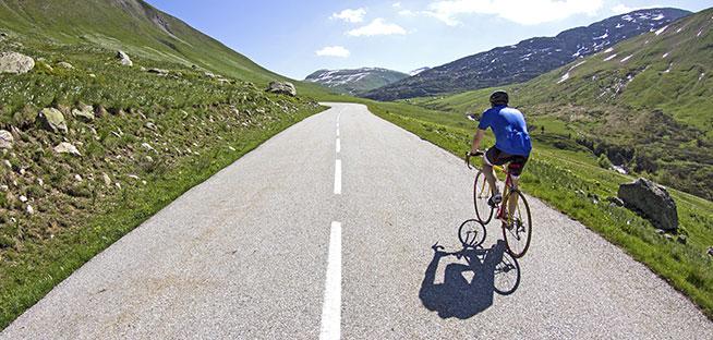 Cyclist riding alone down a winding mountain road.