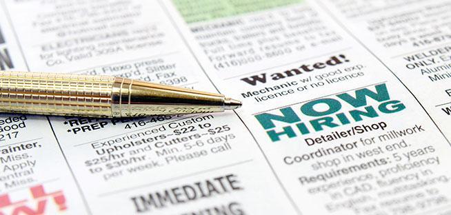Pen on a newspaper job classified section highlighting "NOW HIRING."