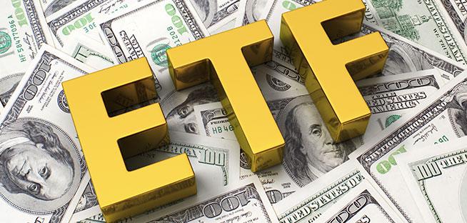 Large gold letters 'ETF' resting on a pile of US dollar banknotes.
