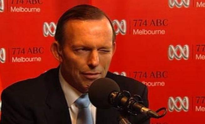 Close-up of Tony Abbott winking while speaking into a microphone.