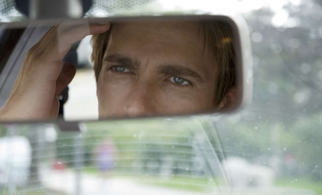 A car dashboard and rear-view mirror with text warning against focusing on the past.