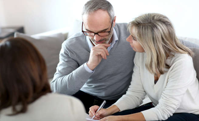 Older couple consulting with a financial advisor on a couch.