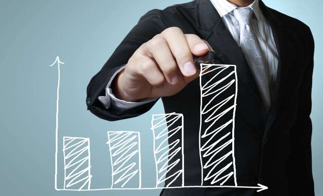 Businessman drawing an upward-trending bar graph.