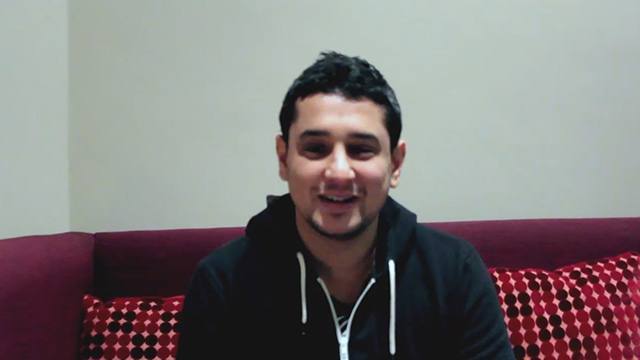 Smiling man seated indoors.