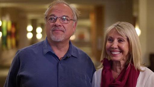 Man and smiling blonde woman standing together in a brightly lit indoor venue.