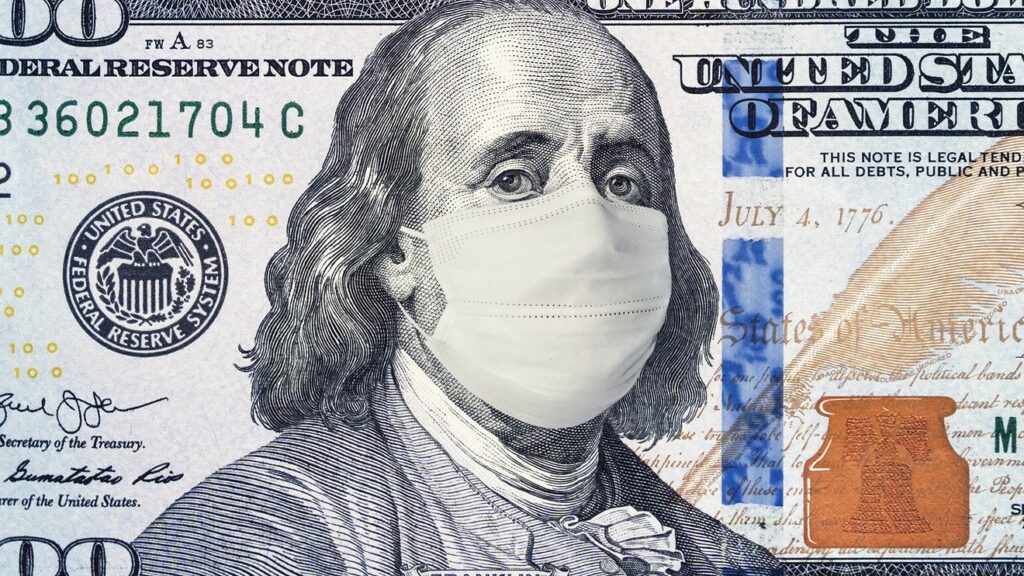 A close-up image of the $100 US dollar bill with Benjamin Franklin wearing a white surgical face mask, symbolizing economic or health concerns.
